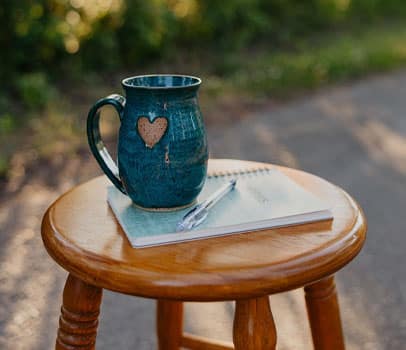 mug and notebook on a stool in the woods